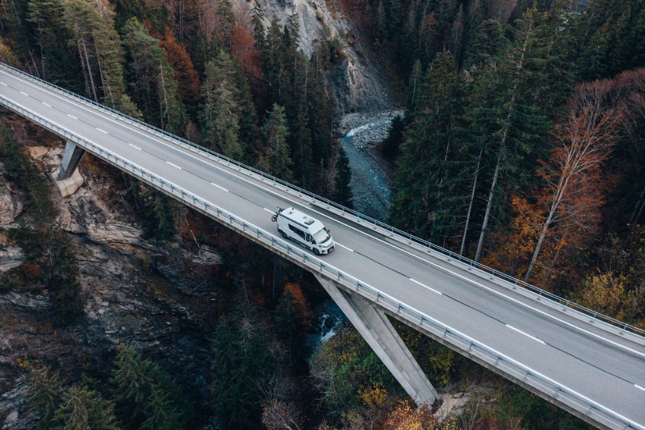 Camper von oben auf einer Brücke in den Schweizer Bergen zum Thema Wohnmobil Schweiz - Verkehrsregeln, Vignette, Maut und Camping